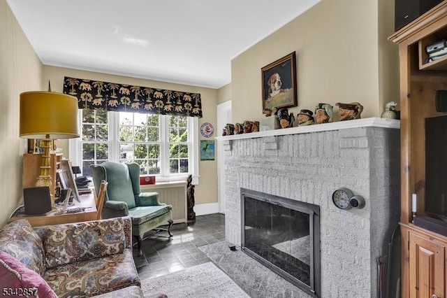 living area featuring a fireplace, baseboards, stone finish floors, and ornamental molding