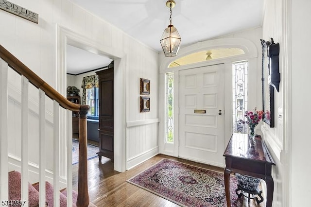 foyer entrance with stairs, a decorative wall, and wood finished floors