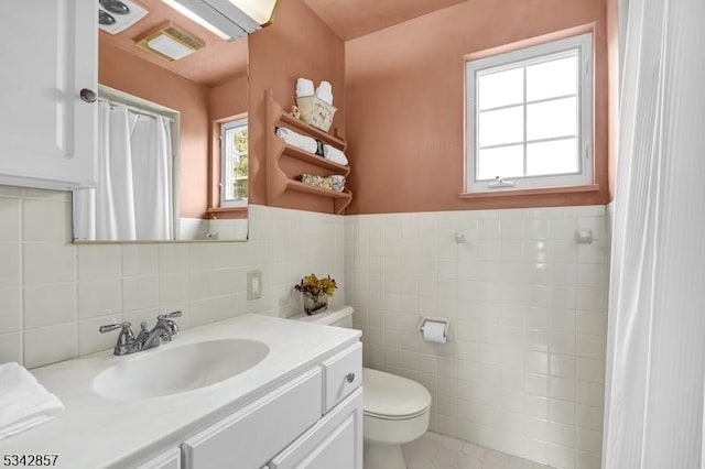 full bathroom featuring tile walls, toilet, vanity, a wainscoted wall, and curtained shower