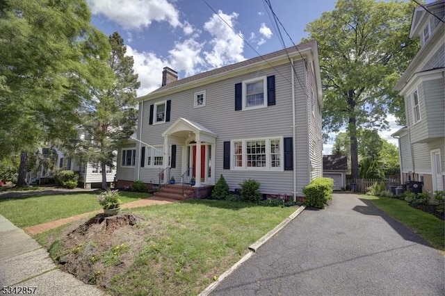 colonial-style house featuring a chimney and a front yard