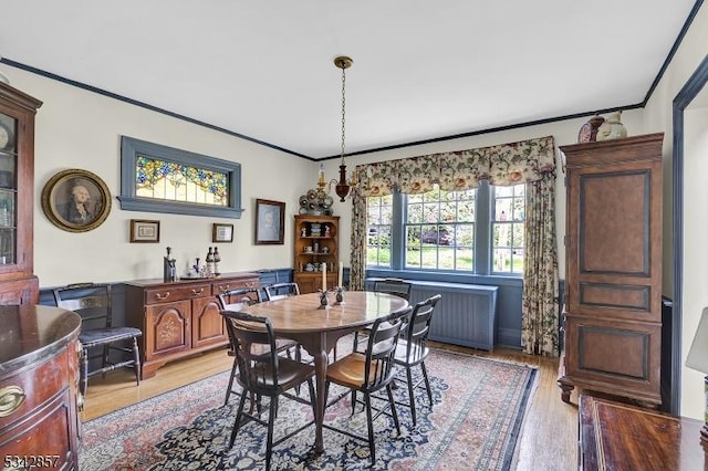 dining space with light wood finished floors and crown molding