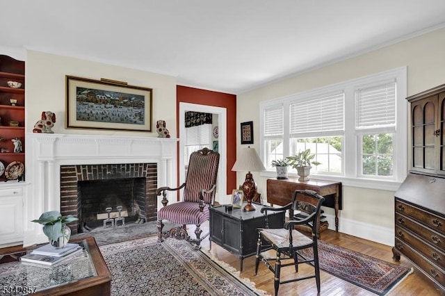 living area featuring baseboards, wood finished floors, and a tile fireplace