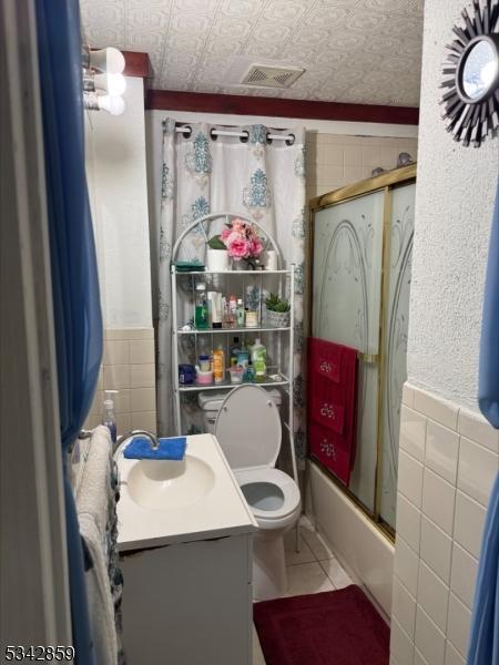 full bath with visible vents, an ornate ceiling, tile patterned floors, vanity, and tile walls