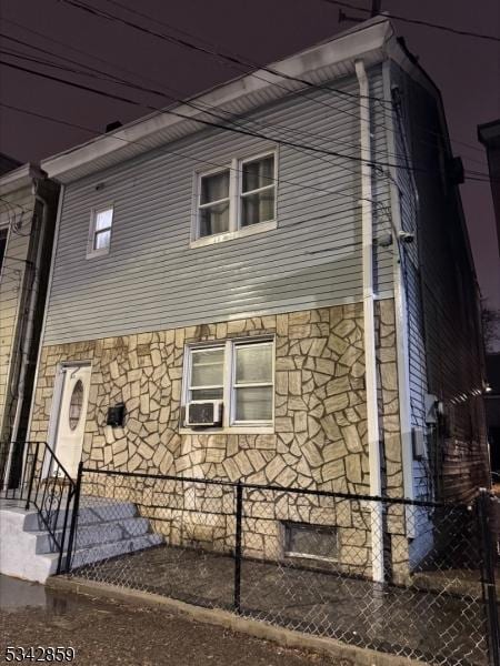 view of side of home with stone siding and fence