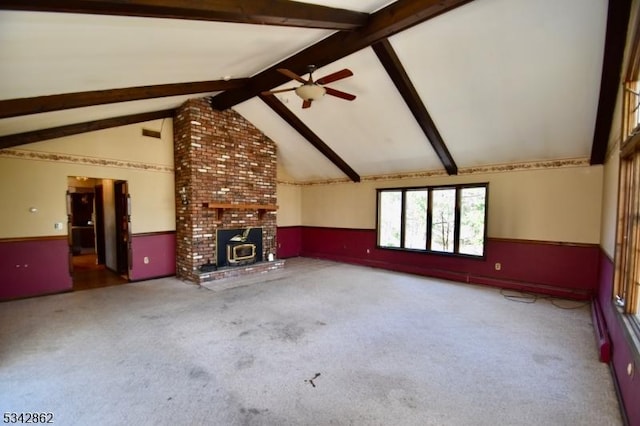 unfurnished living room featuring carpet flooring, wainscoting, lofted ceiling with beams, and a ceiling fan