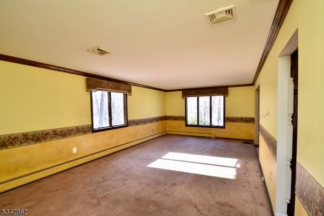 empty room with carpet, plenty of natural light, visible vents, and a wainscoted wall