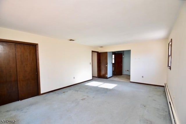 unfurnished bedroom featuring visible vents, baseboards, multiple closets, light colored carpet, and baseboard heating