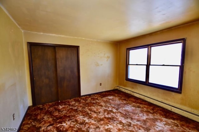 unfurnished bedroom with a closet and baseboard heating