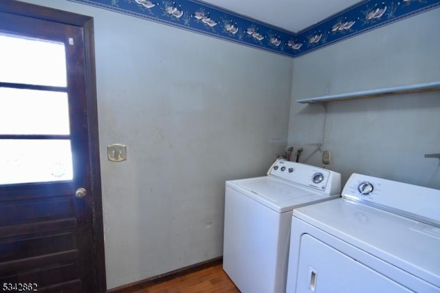 laundry room with dark wood-type flooring, a healthy amount of sunlight, washing machine and dryer, and laundry area