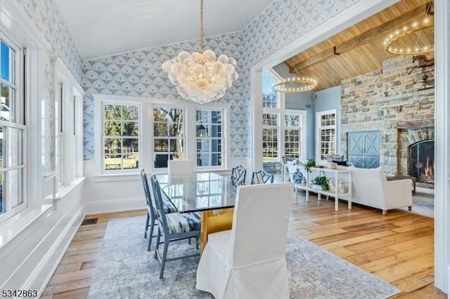 sunroom / solarium featuring an inviting chandelier, plenty of natural light, a fireplace, and lofted ceiling