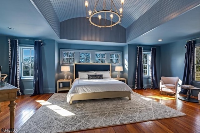 bedroom with baseboards, lofted ceiling, an inviting chandelier, and wood-type flooring