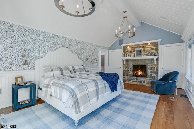 bedroom with lofted ceiling with beams, wood finished floors, a wainscoted wall, and a chandelier