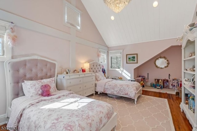 bedroom with lofted ceiling, a notable chandelier, and wood finished floors