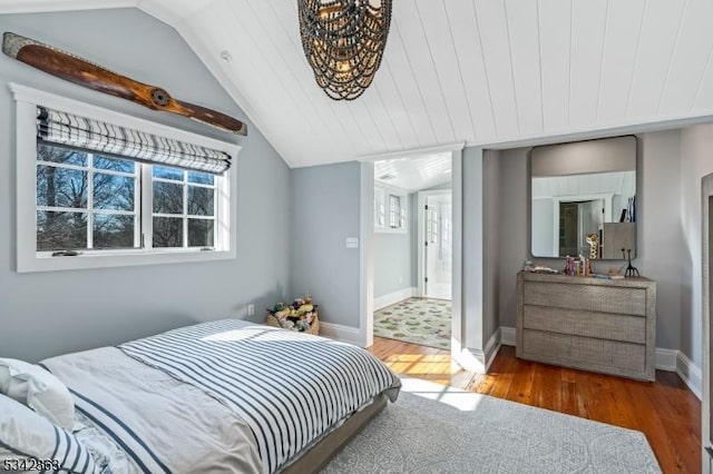 bedroom featuring baseboards, lofted ceiling, and wood finished floors