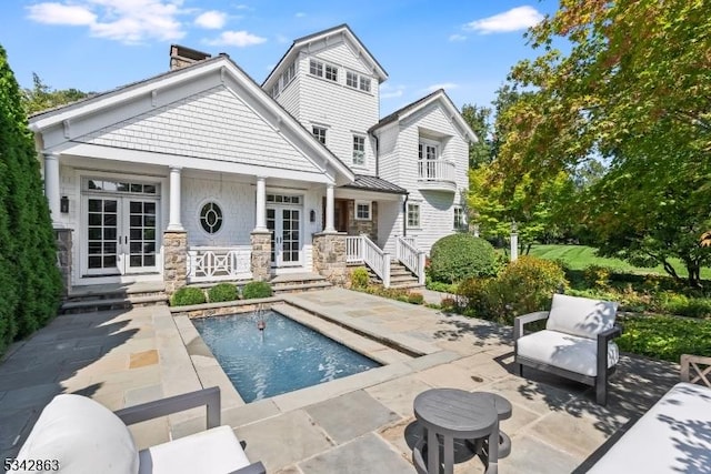 back of property featuring an outdoor pool, french doors, and a patio area