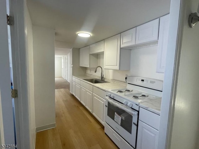 kitchen with a sink, electric range, light wood-style flooring, and white cabinetry