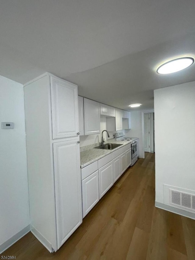 kitchen with visible vents, white range with gas cooktop, a sink, wood finished floors, and light countertops