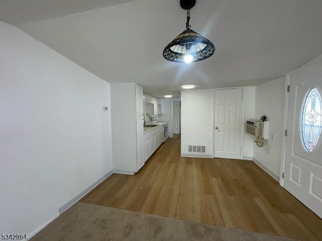 entryway with a wall unit AC, baseboards, visible vents, and light wood finished floors