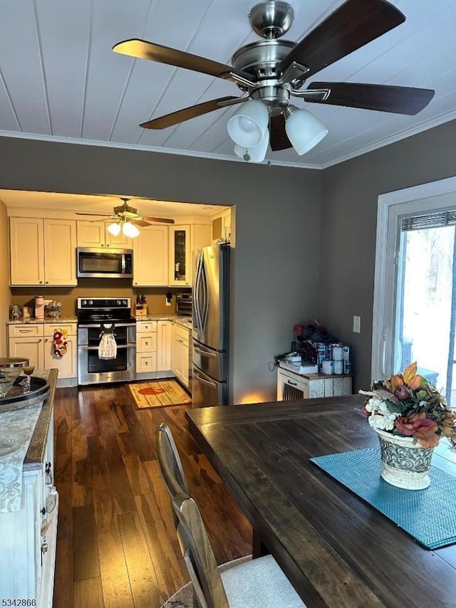 kitchen with dark wood-type flooring, stainless steel appliances, crown molding, and ceiling fan