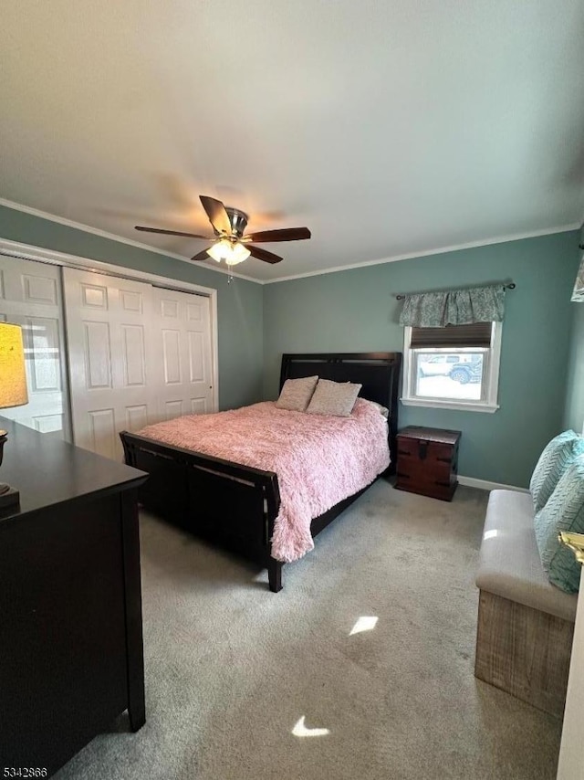 carpeted bedroom with baseboards, a ceiling fan, a closet, and ornamental molding