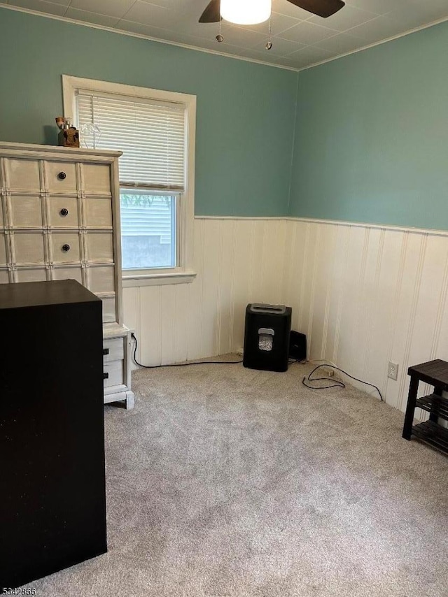 carpeted bedroom with wainscoting and ceiling fan