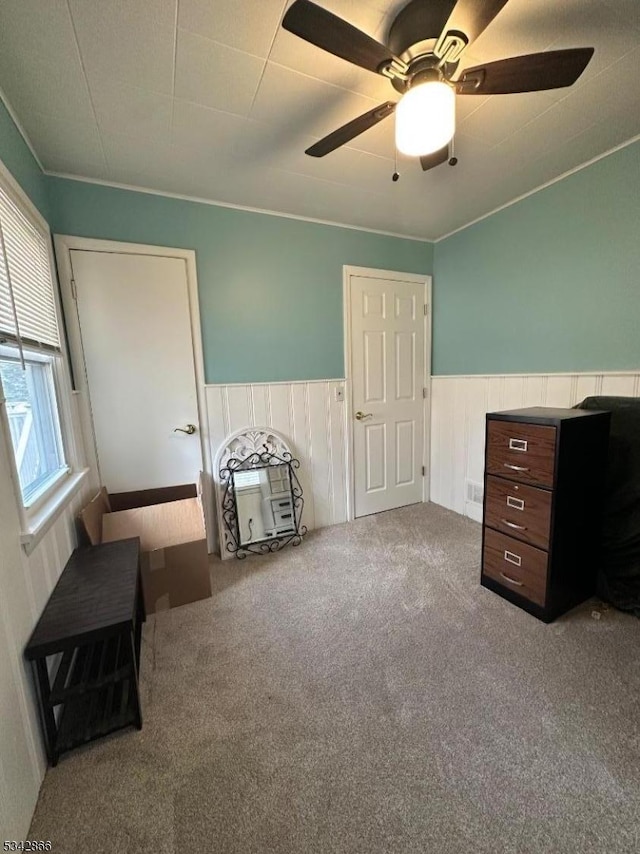 unfurnished bedroom featuring a ceiling fan, carpet, and wainscoting