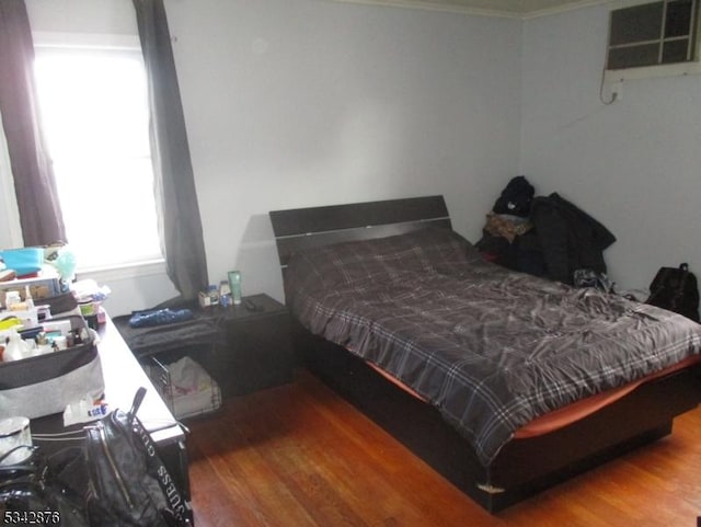 bedroom featuring wood finished floors and a wall mounted AC