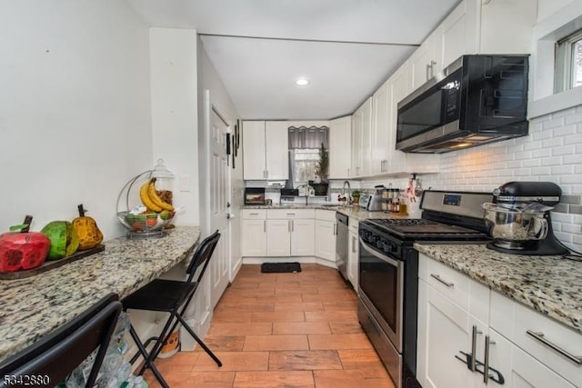 kitchen with light stone countertops, decorative backsplash, recessed lighting, appliances with stainless steel finishes, and white cabinets