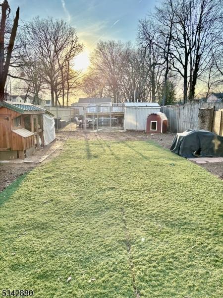 yard at dusk with an outdoor structure, a fenced backyard, and exterior structure