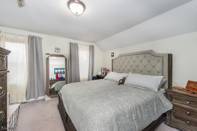 bedroom featuring multiple windows, lofted ceiling, and light colored carpet