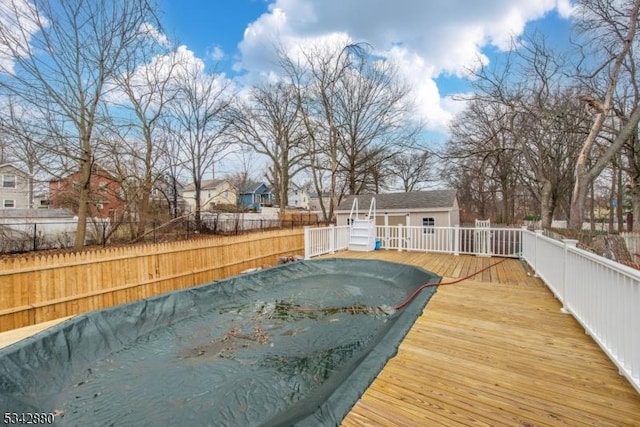 view of pool featuring an outbuilding, a fenced backyard, a fenced in pool, and a wooden deck