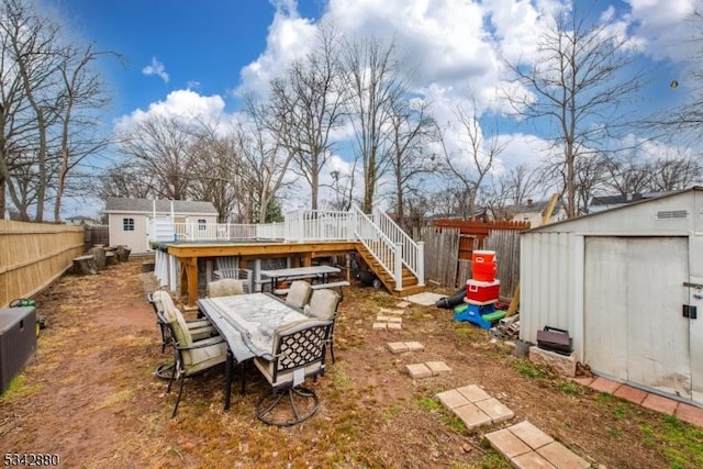 view of yard featuring a storage unit, a deck, a fenced backyard, an outdoor structure, and outdoor dining area