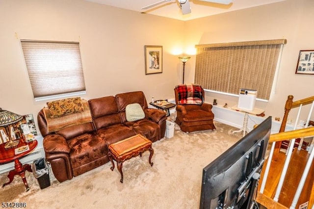 living room featuring carpet floors, ceiling fan, and stairs