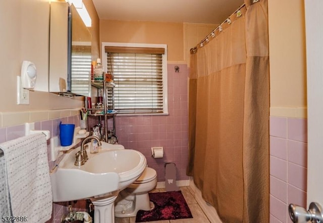 full bathroom featuring a shower with curtain, tile walls, toilet, and a sink