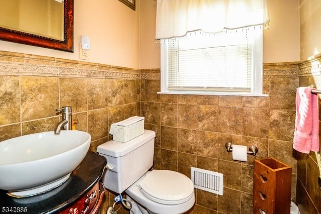 bathroom with visible vents, toilet, tile walls, and vanity