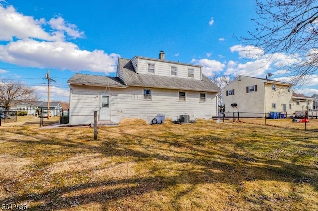 back of house featuring a lawn, fence, and central AC