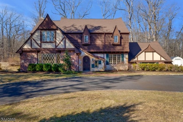 tudor-style house with brick siding and a front lawn