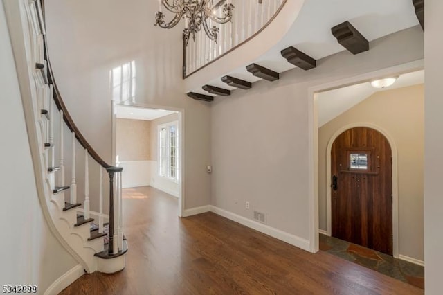 entrance foyer with visible vents, wood finished floors, arched walkways, baseboards, and stairs