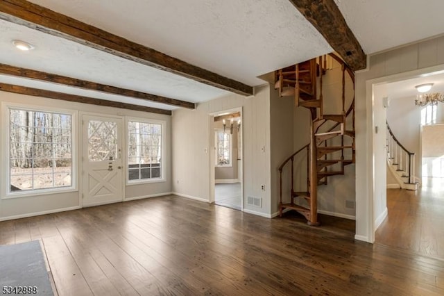 unfurnished living room featuring hardwood / wood-style floors, stairway, baseboards, visible vents, and beam ceiling