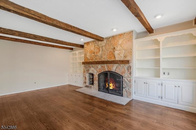 unfurnished living room featuring built in shelves, baseboards, beam ceiling, a fireplace, and wood finished floors