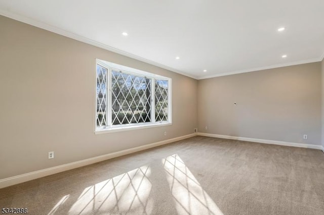 empty room featuring crown molding, carpet, and baseboards