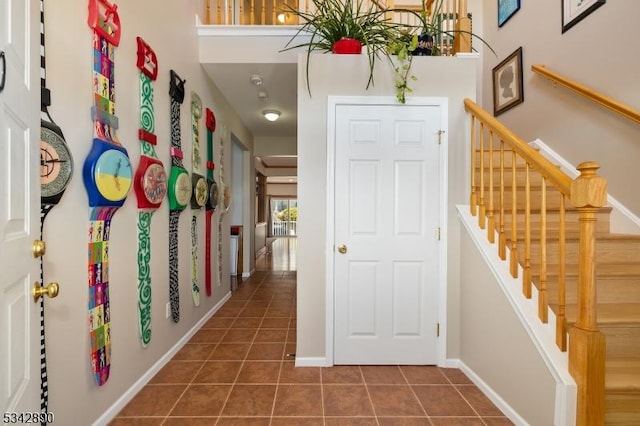 entryway with tile patterned flooring, stairs, and baseboards