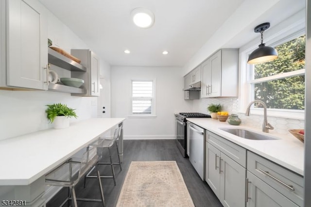 kitchen featuring under cabinet range hood, dishwasher, light countertops, decorative backsplash, and a sink