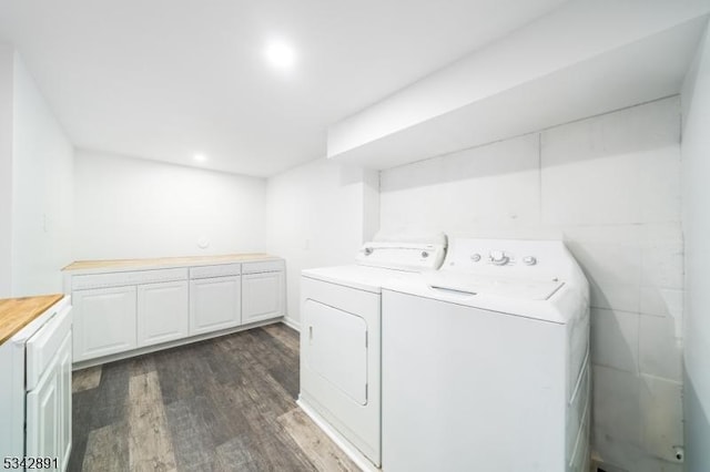 clothes washing area with dark wood-type flooring, cabinet space, and washer and clothes dryer