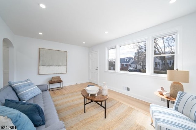 living area with wood finished floors, visible vents, arched walkways, and a healthy amount of sunlight