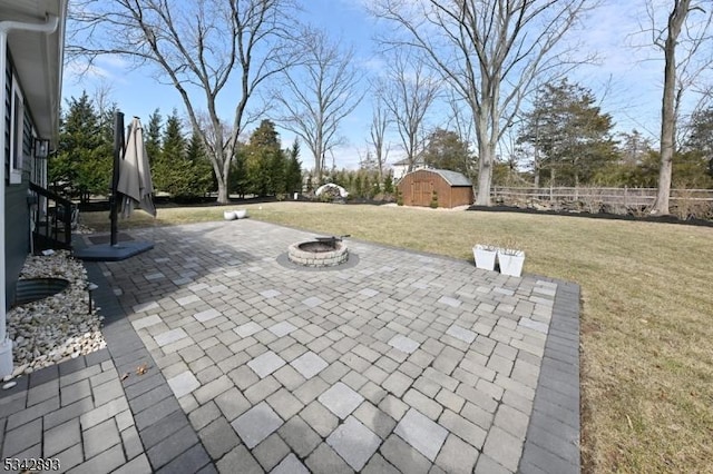 view of patio / terrace featuring an outdoor fire pit, a storage shed, an outdoor structure, and fence