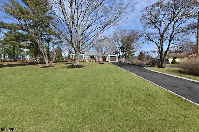 view of yard with aphalt driveway and a detached garage