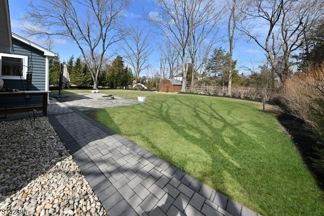 view of yard featuring an outdoor structure, a storage shed, a patio, and fence