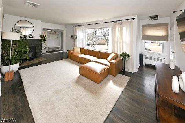 living room with radiator heating unit, dark wood-style floors, visible vents, and a wealth of natural light