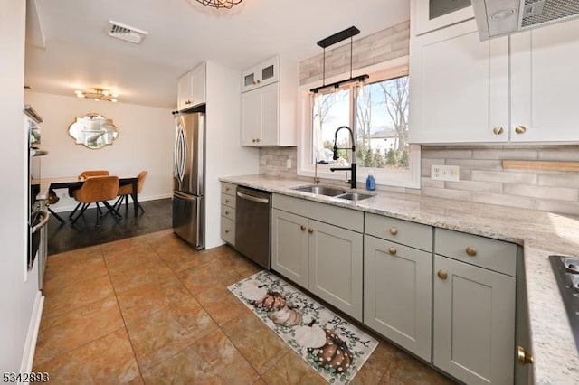 kitchen with visible vents, glass insert cabinets, decorative backsplash, appliances with stainless steel finishes, and a sink